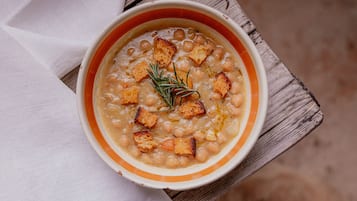 Eine Schüssel Suppe mit Croutons und einem Rosmarinzweig auf einer Holztischplatte.