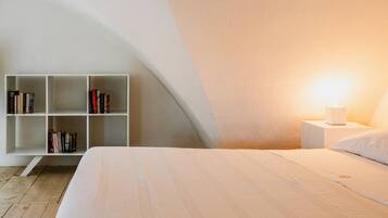 Une chambre à coucher avec un lit, une bibliothèque blanche et une table de chevet avec une lampe.