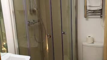 A corner bathroom with a glass-enclosed shower, a toilet, and a sink.
