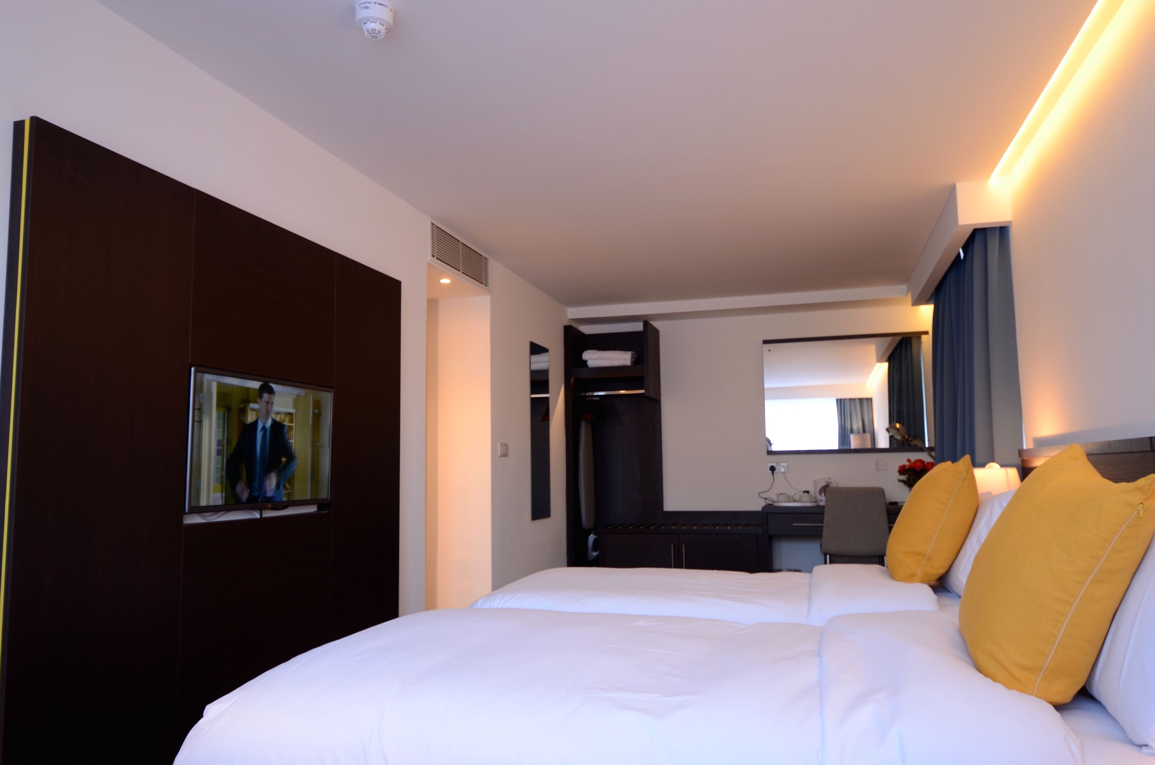 Ein Hotelzimmer mit einem großen Bett, einem Schreibtisch, einem Stuhl, einem Spiegel und einem Fernseher.