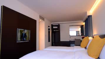 Ein Hotelzimmer mit einem großen Bett, einem Schreibtisch, einem Stuhl, einem Spiegel und einem Fernseher.