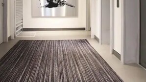 A modern hallway with a patterned carpet, a large abstract artwork on the wall, and a series of doors and elevators. - Pelican London Hotel and Residence (London)