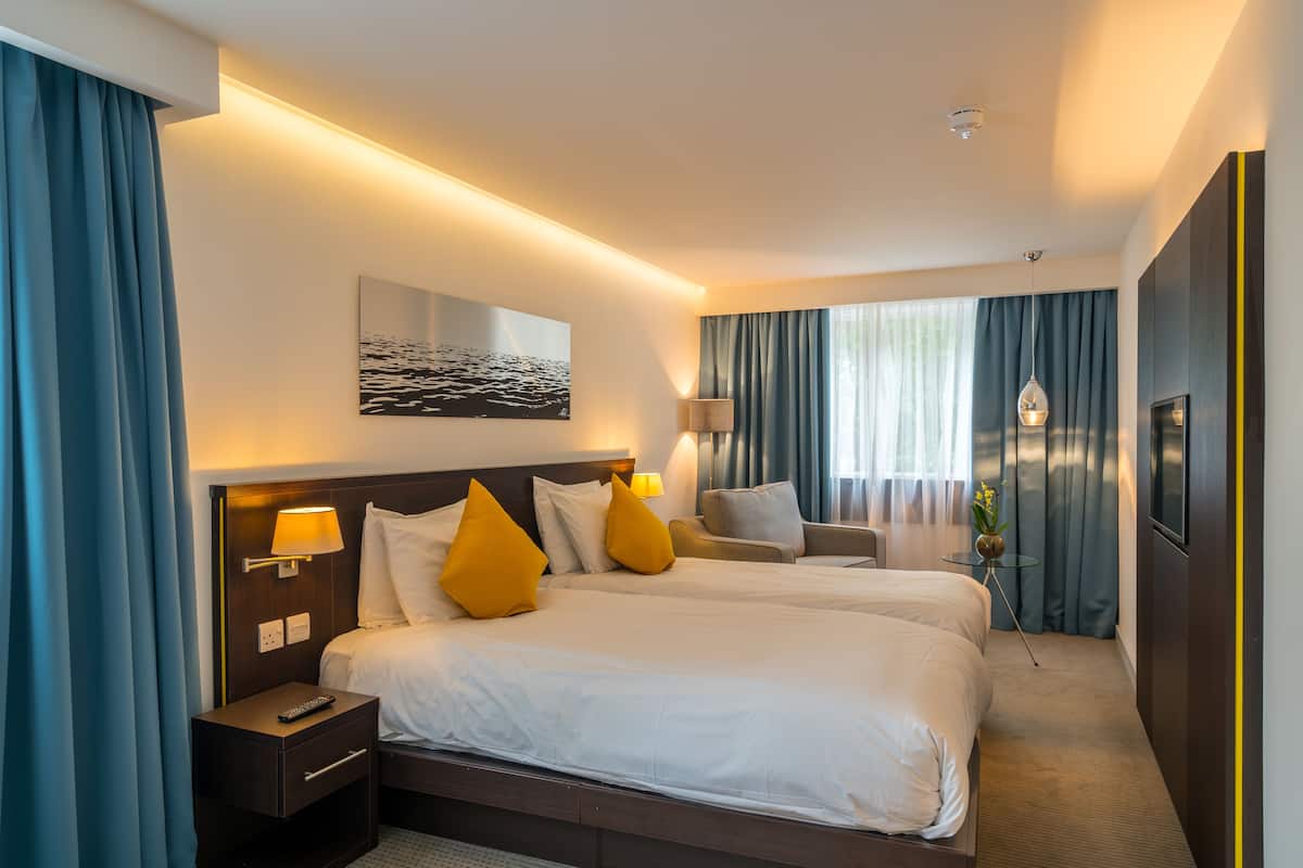 Ett hotellrum med två sängar, en soffa, en tv och en tavla på väggen.
