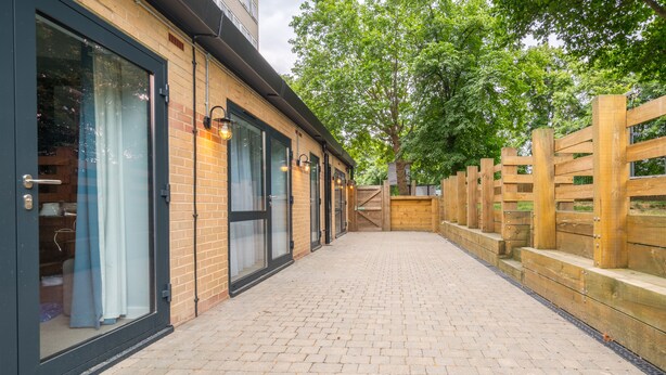 A brick building with large windows and a wooden fence. - Pelican London Hotel and Residence (London)