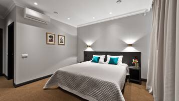 Un dormitorio moderno con una cama grande, dos lámparas de pared, una mesita de noche y un equipo de aire acondicionado.