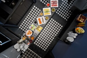 Una cucina con pavimento a scacchi, diversi alimenti e utensili.