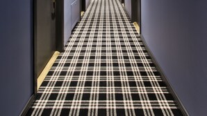 A hallway with a checkered floor, doors on both sides, and a ceiling with a clock and a guitar design. - 15th Avenue Hotel (Vilnius)