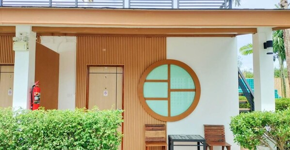 Une entrée moderne avec une façade en bois, une fenêtre de forme circulaire et un panneau indiquant une réduction pour les clients d’AIS TOURIST.