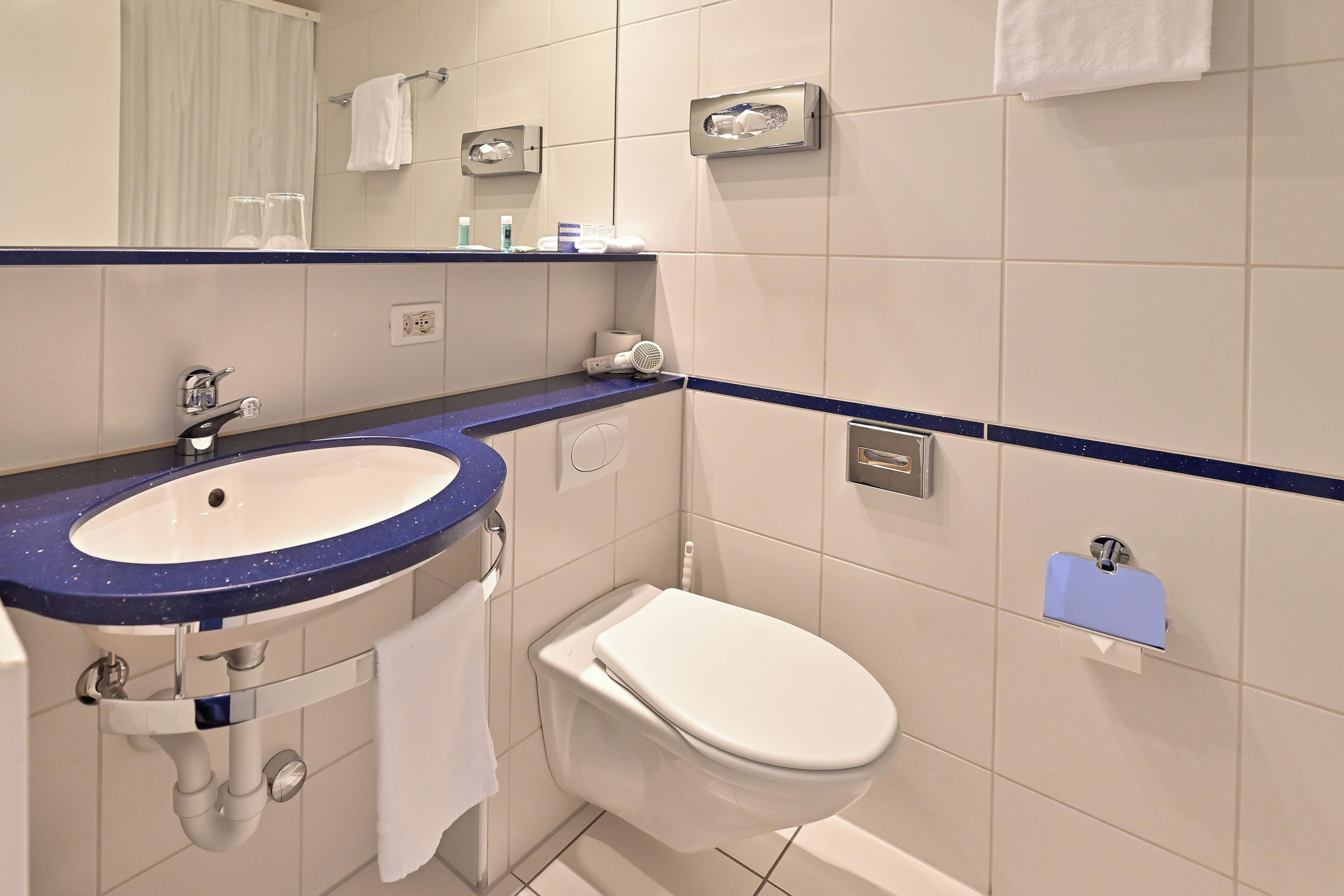 A bathroom with a white sink, a toilet, and a mirror.