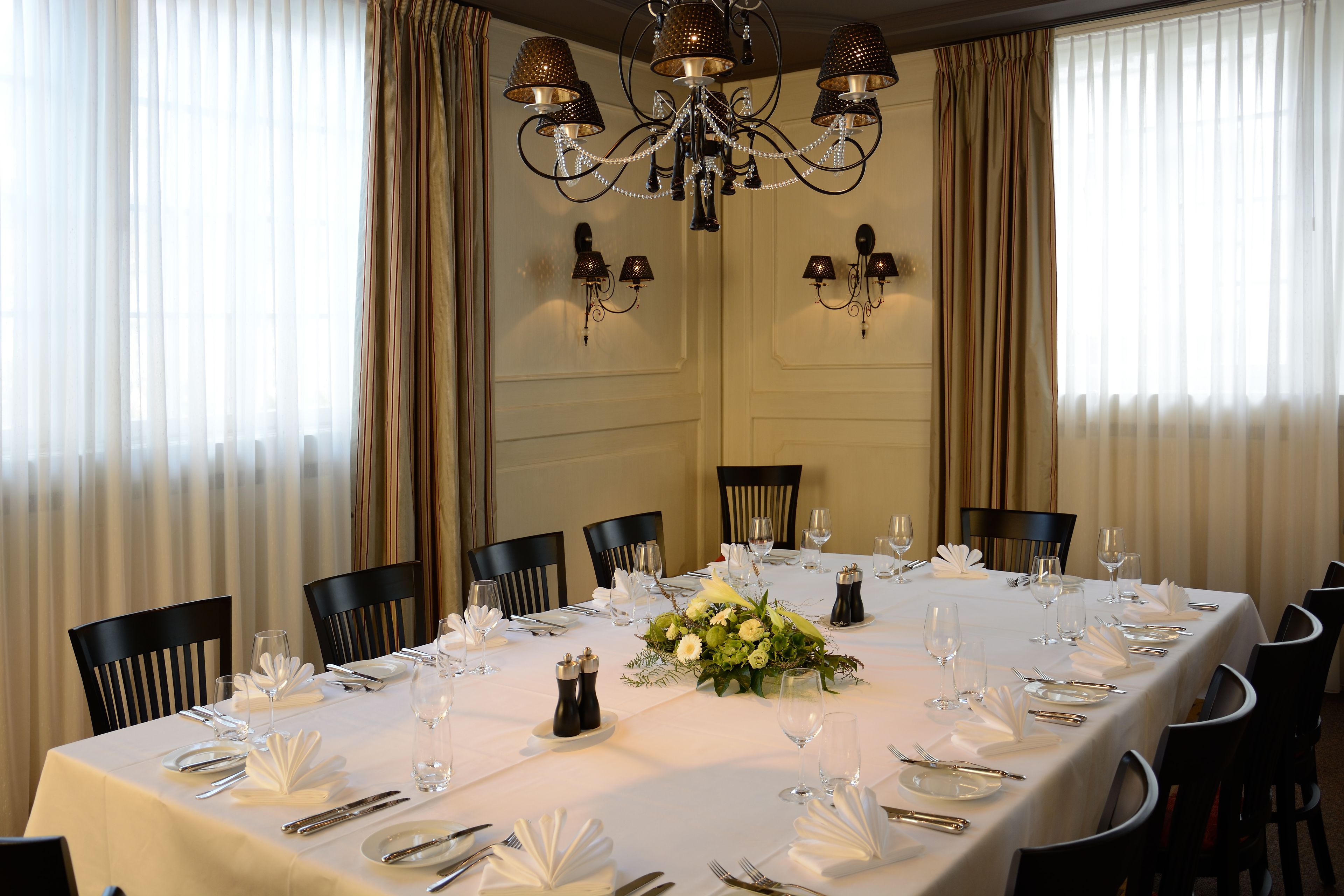 A dining room with a long table set for a meal, surrounded by chairs.