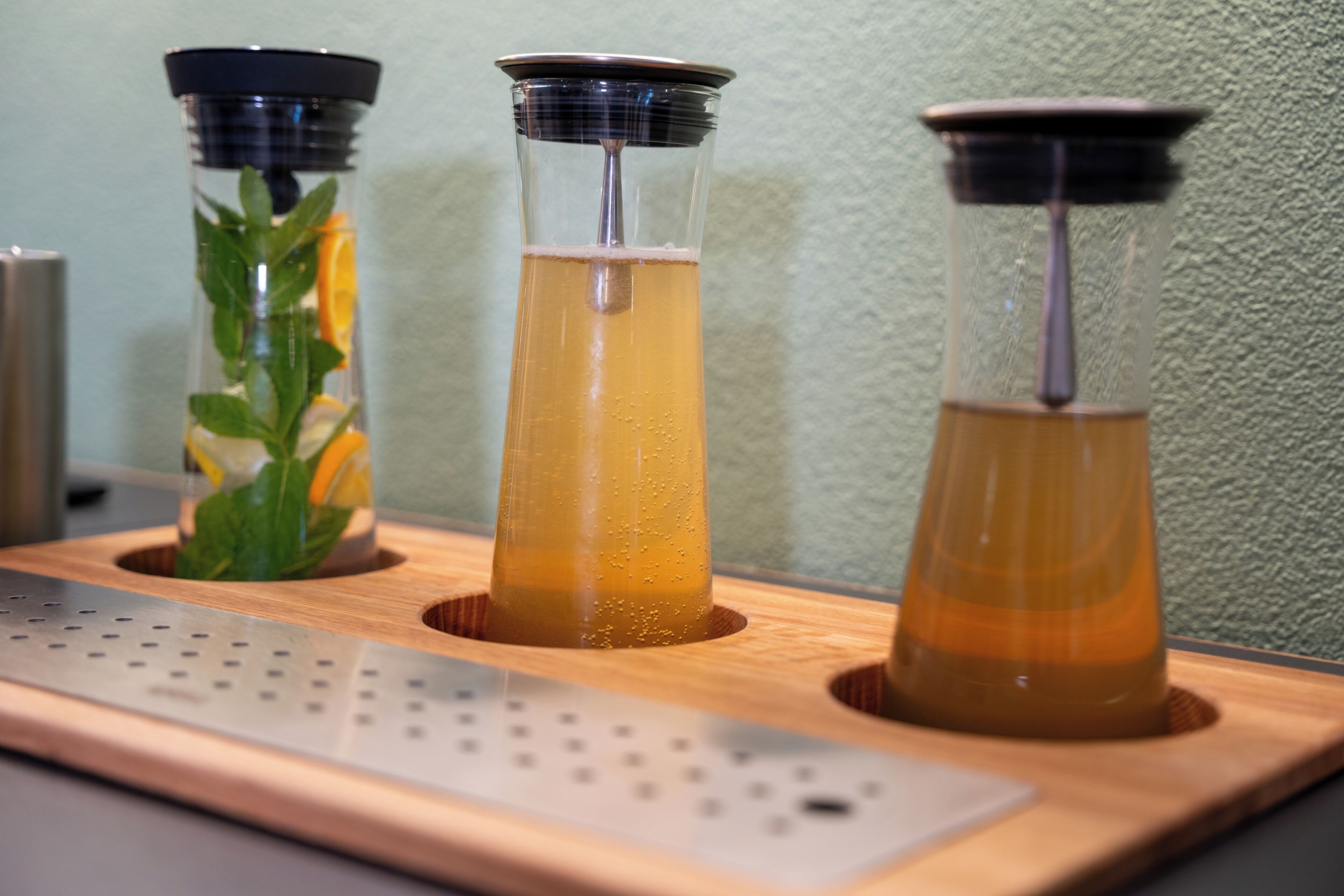 Three glass containers with different colored liquids on a wooden tray.