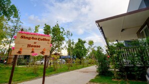 Un letrero de madera anuncia Sing-ha Coffee & House, con un camino que lleva a un edificio.