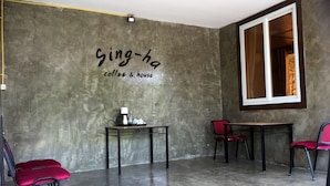 Una habitación con pared de concreto, una mesa y sillas, y una ventana.