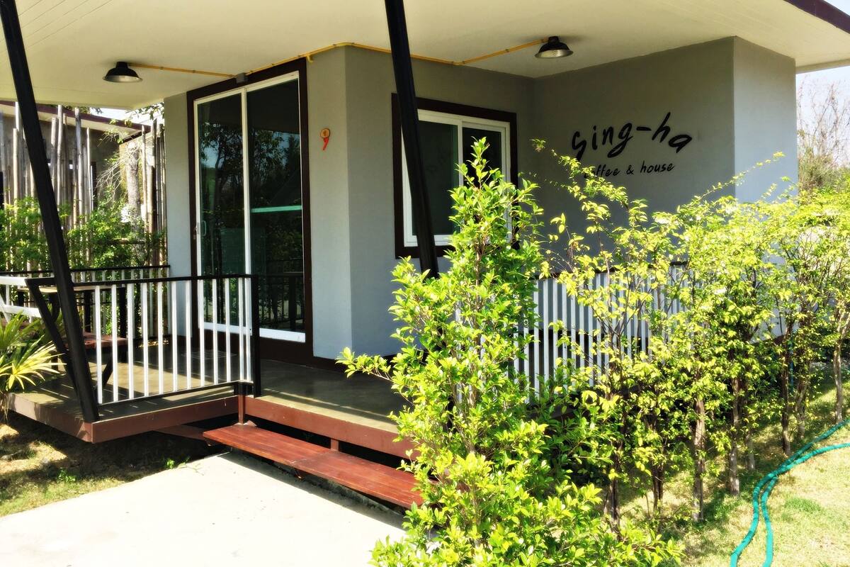 A building with a covered porch, a sign reading "king-ha coffee & house", and a small garden area with a bench.