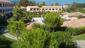A resort with multiple buildings, a swimming pool, and lush greenery.
