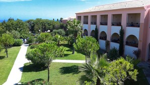 A hotel with a central courtyard, multiple balconies, and a view of the sea.