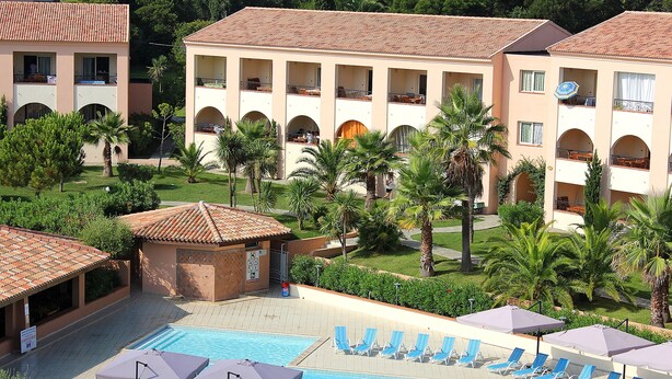 A resort with a swimming pool, lounge chairs, and a building with multiple balconies.