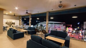 A spacious indoor area with multiple seating arrangements, including sofas and tables, and a view of the cityscape through large windows.