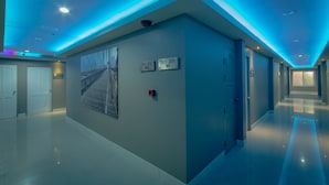A modern hallway with directional signs, a fire alarm, and a large window with a view of a bridge.