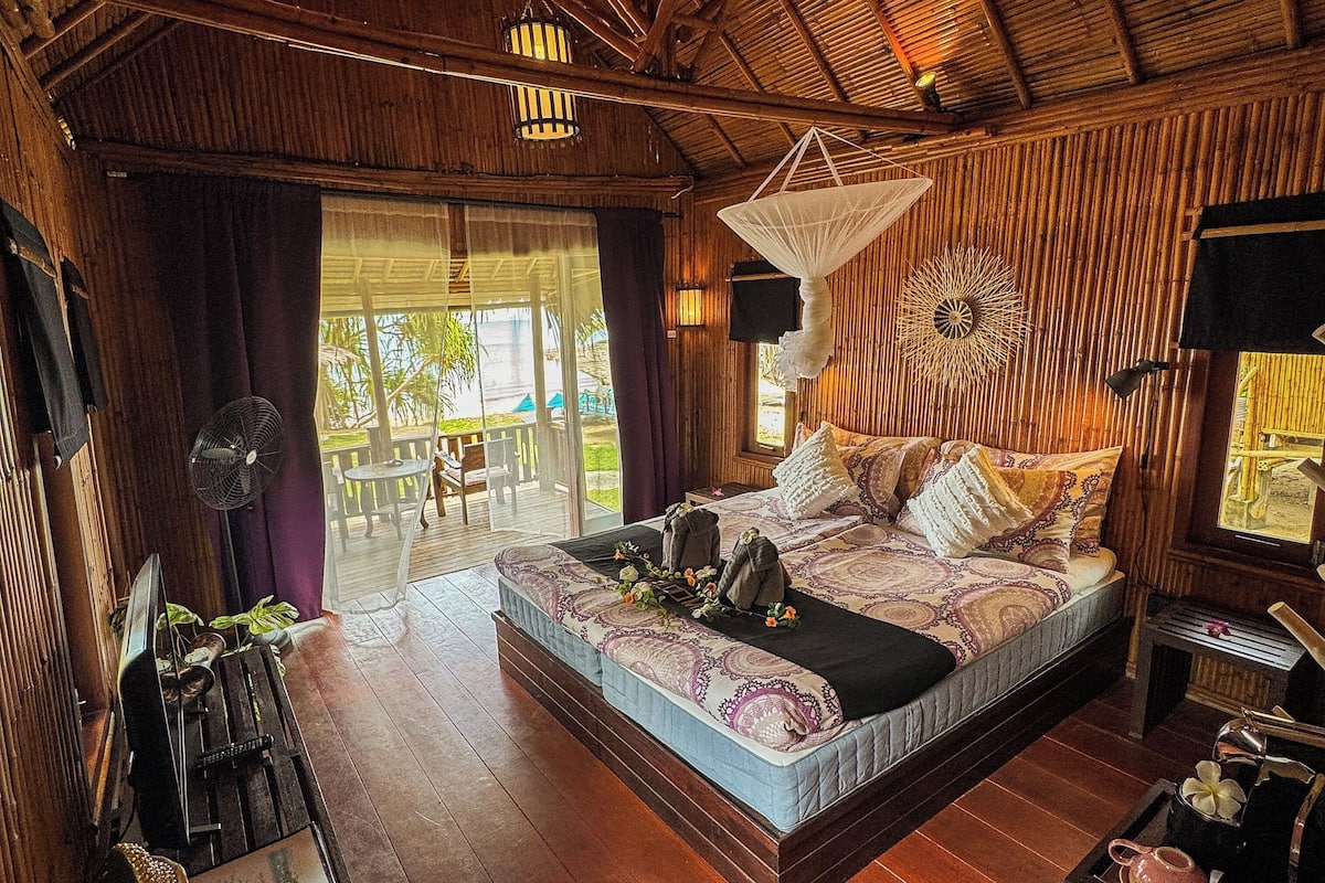 A spacious bedroom with a large bed, a fan, and a view of the outdoors.