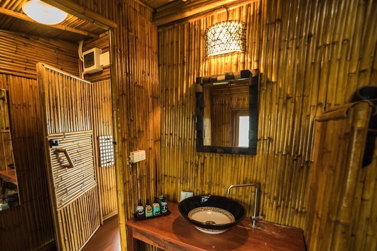 A bathroom with a wooden interior, a sink with a basin, a mirror, and a window.