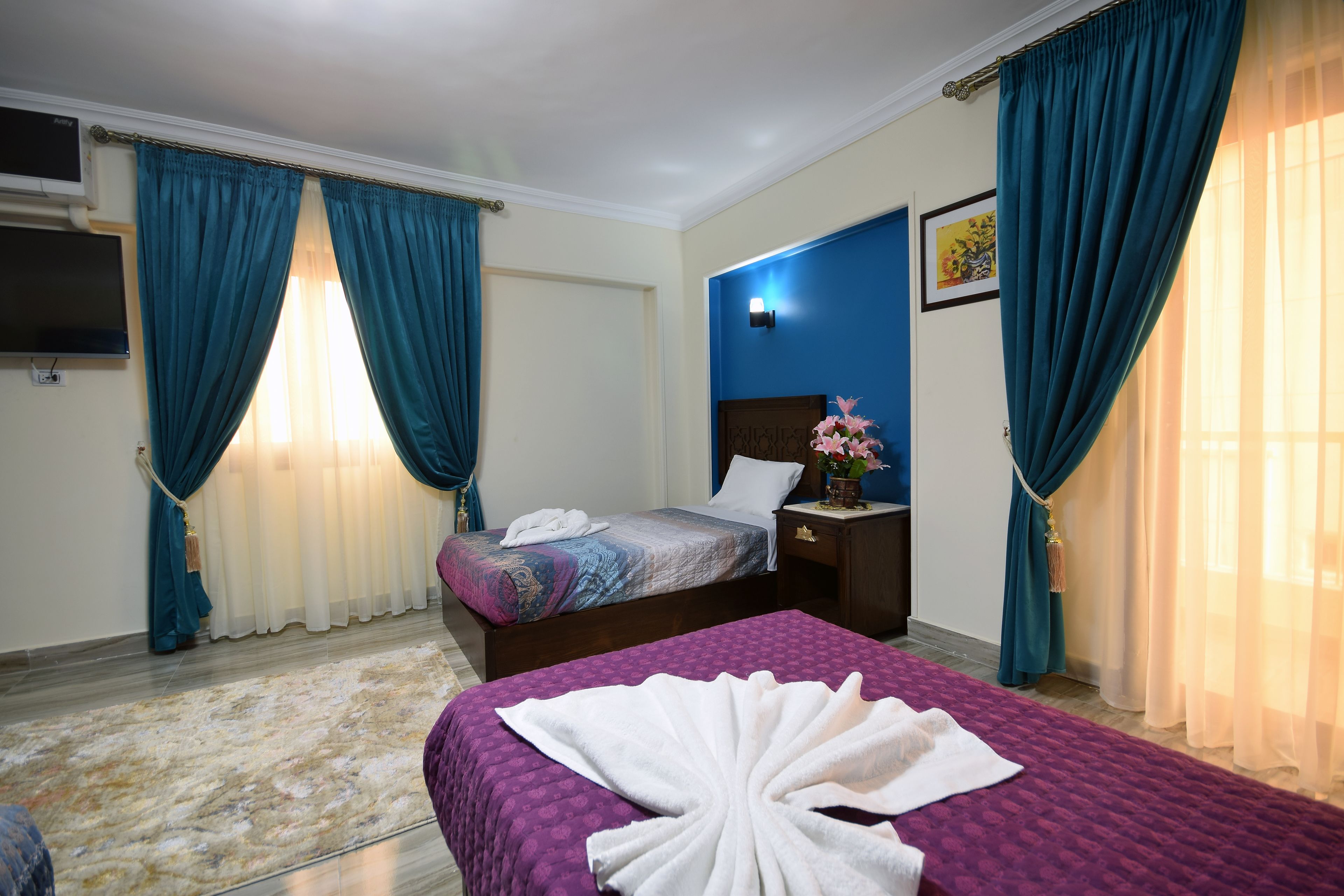 A hotel room with a bed, a nightstand, a TV, and curtains.