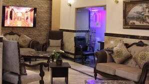 Un vaste salon doté d’un haut plafond, de poutres apparentes, d’un téléviseur à écran plat fixé au mur et d’un coin salon confortable avec des canapés et des fauteuils.