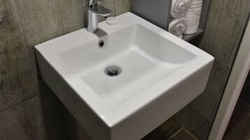 Un lavabo blanc pour la salle de bain, doté d’un robinet chromé et d’un distributeur de savon.
