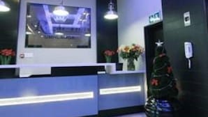 A reception area with a modern design, featuring a reception desk, a large screen, and a Christmas tree. - Regal Inn Gateway Umhlanga (Umhlanga)