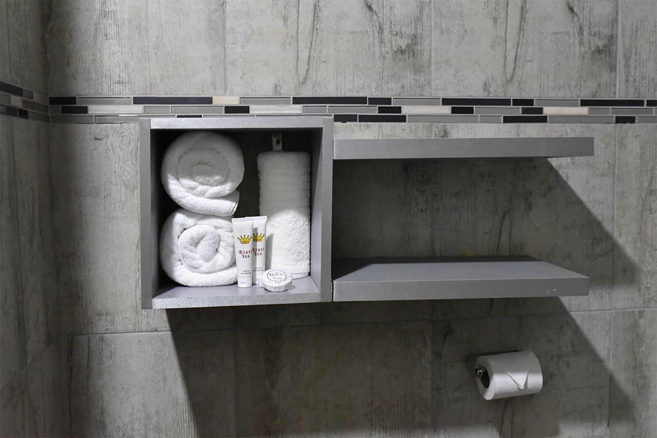 Un bagno con un portasciugamani pieno di asciugamani e una bottiglia di lozione.