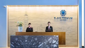 A reception desk with a marble top and a backdrop featuring a cityscape and a pagoda. - Plaza Premium Lounge Terminal 2 Zone A (Taoyuan City)