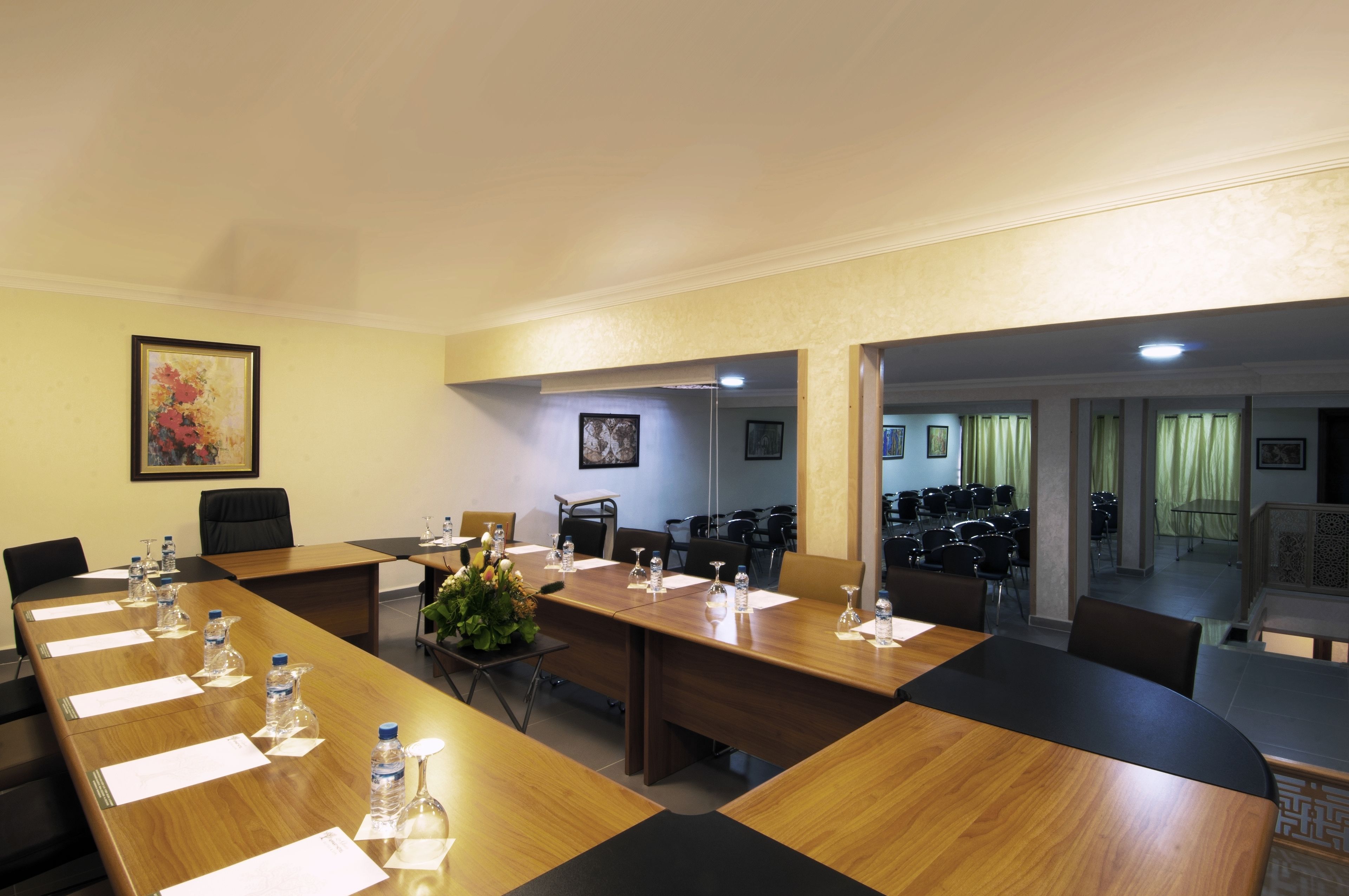 A conference room with a long wooden table, chairs, water bottles, and a vase with flowers.