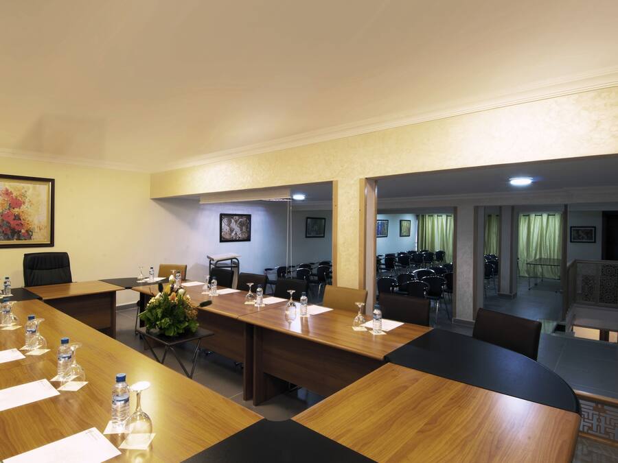 A conference room with a long wooden table, chairs, water bottles, and a vase with flowers.