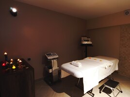 Un cuarto de spa con camilla de masaje, velas, sillón de masajes y equipo de masaje.