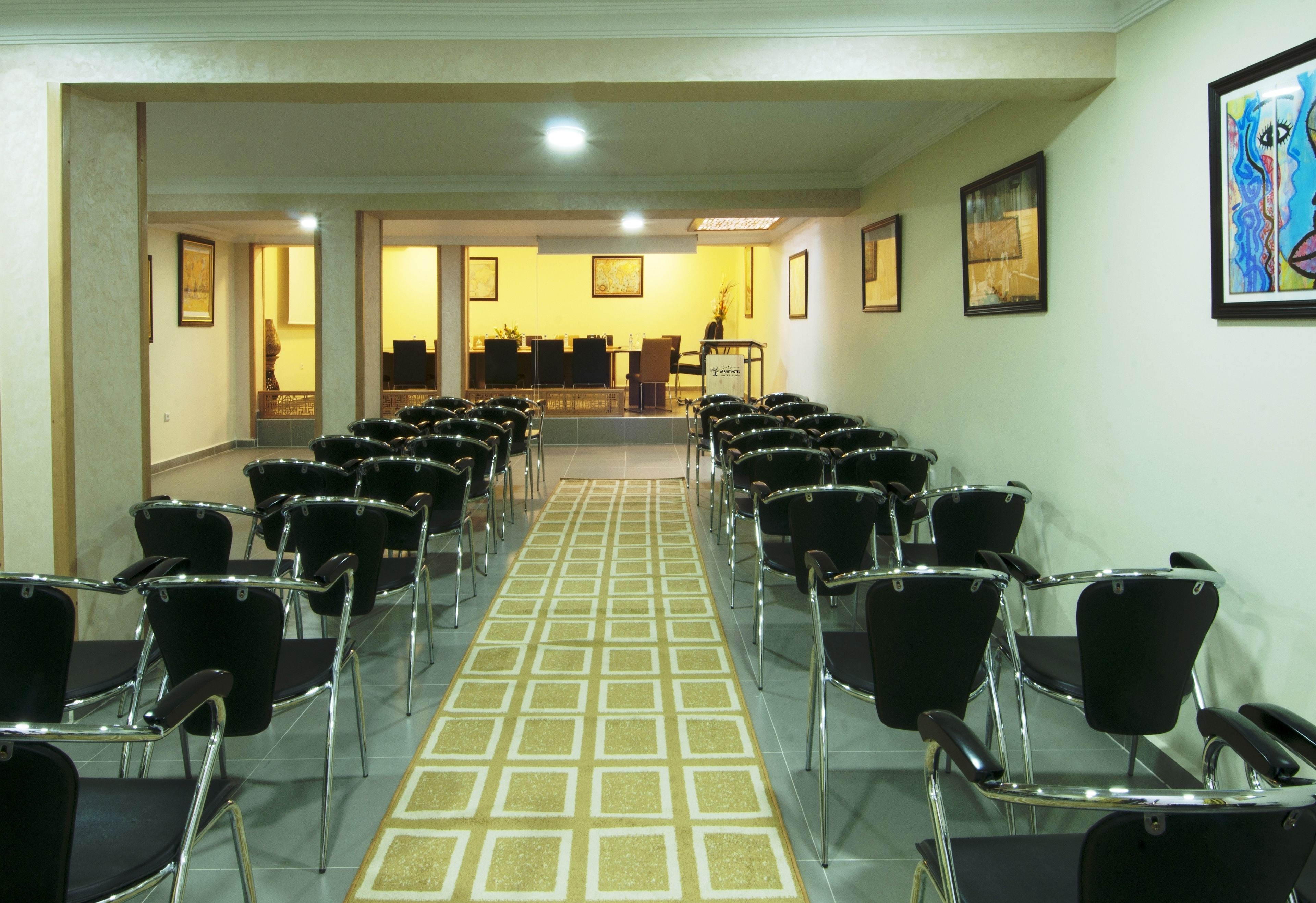Un hall de hotel con filas de sillas negras orientadas hacia una recepción.
