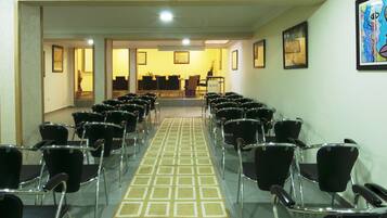 Un hall de hotel con filas de sillas negras orientadas hacia una recepción.