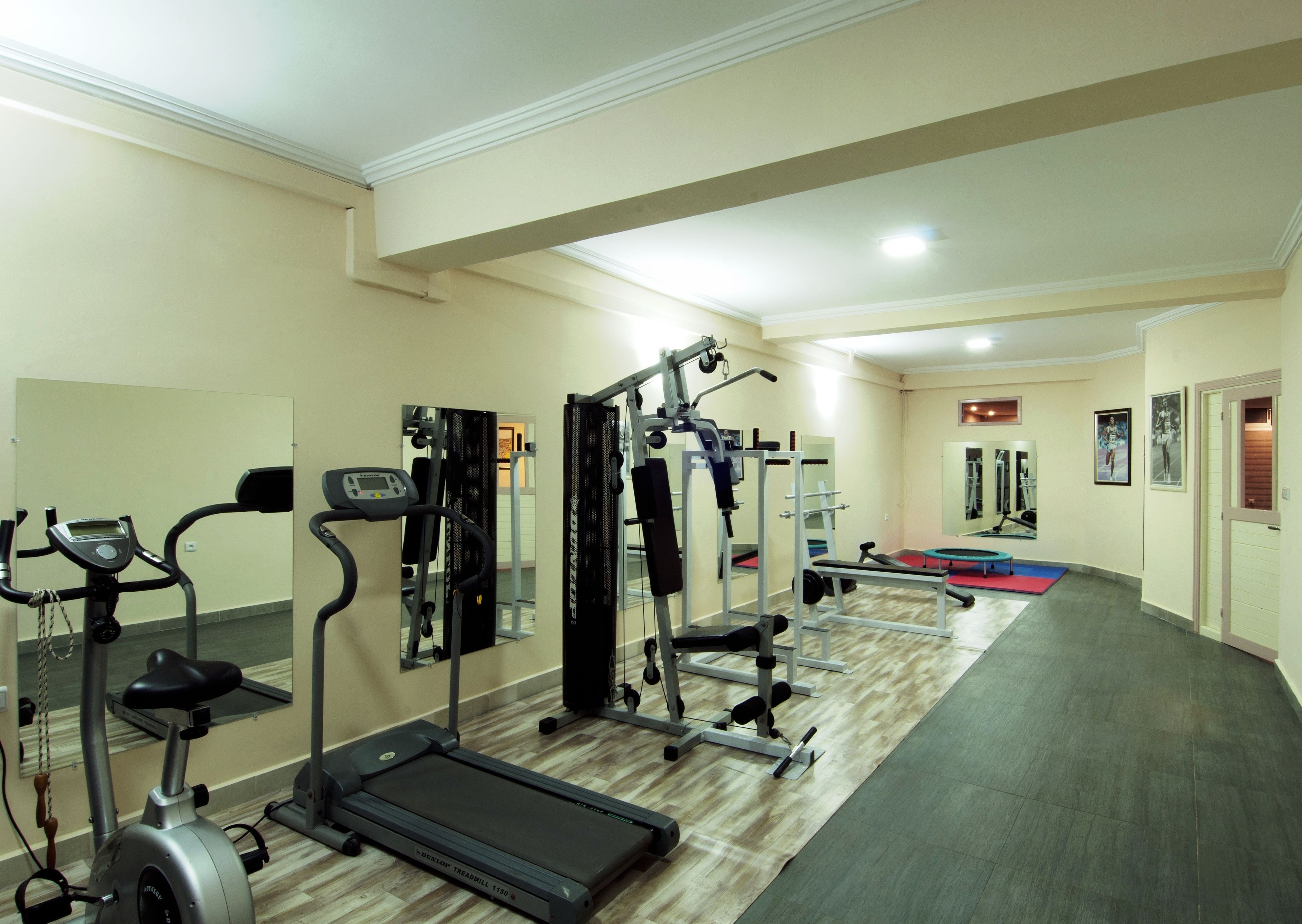 A gym with treadmills, weight machines, and a mirrored wall.