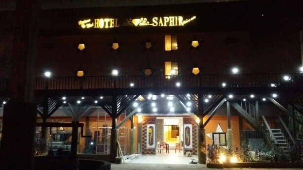 The exterior of the HOTEL SAPHIR with a prominent sign, a covered entrance, and a staircase leading to the entrance. - Hotel Saphir (Abidjan)
