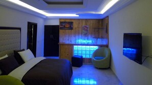 A modern bedroom with a bed, a chair, and a TV. - Hotel Saphir (Abidjan)