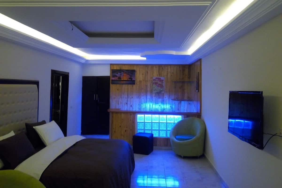 A modern bedroom with a bed, a chair, and a TV.