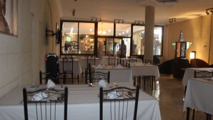 A restaurant with multiple tables and chairs, large windows, and a bar area visible through the windows. - Hotel Saphir (Abidjan)