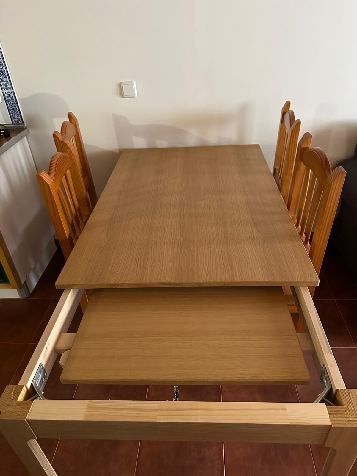 Una mesa de comedor con estructura de madera y una extensión plegable.