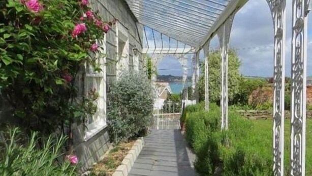 Un sendero cubierto con techo de vidrio que conduce a una casa con vista al mar.