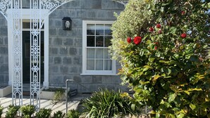 Una casa de piedra con una puerta blanca, una ventana y un jardín con rosas rojas.