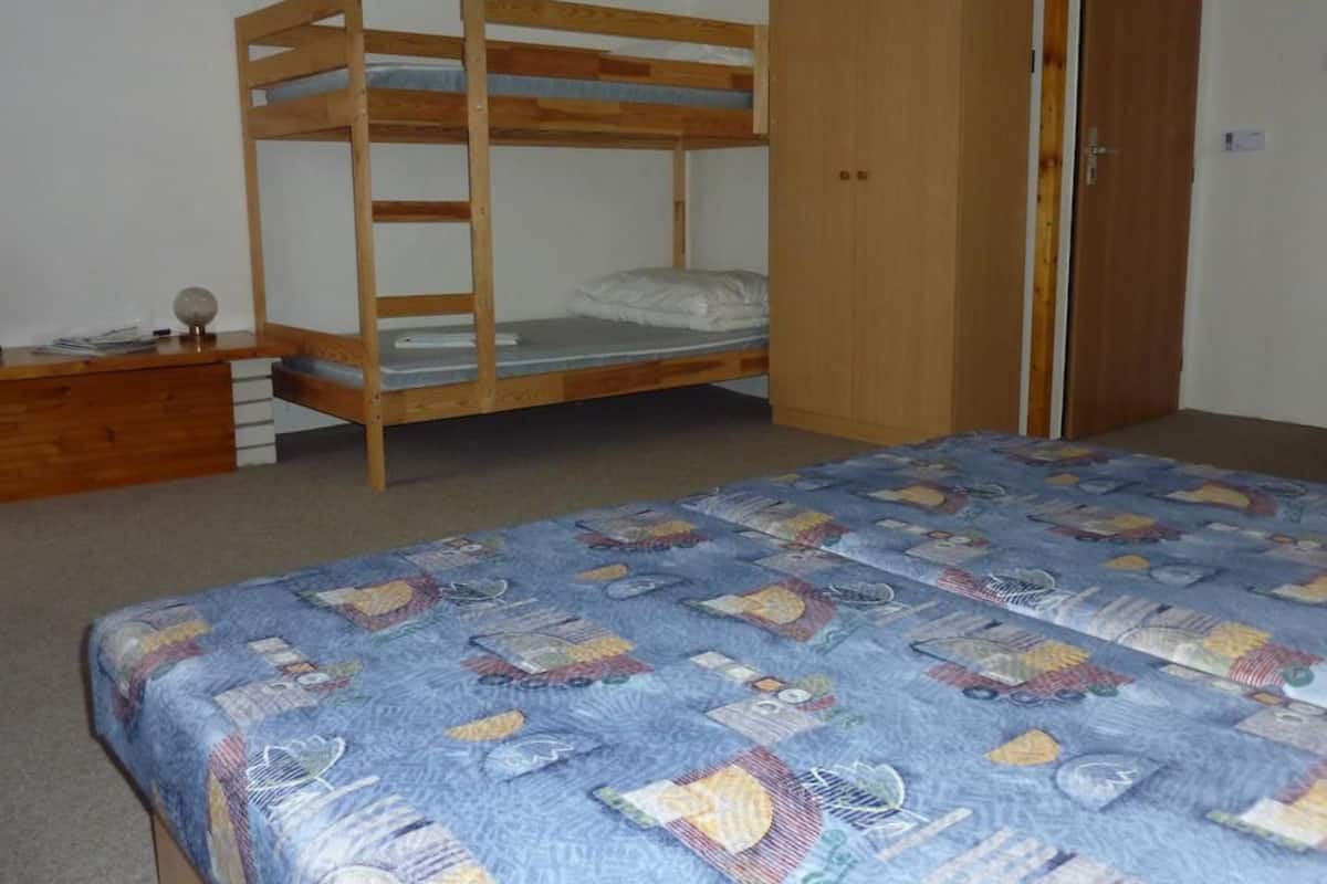 Dormitorio con literas, un armario de madera y una colcha acolchada.