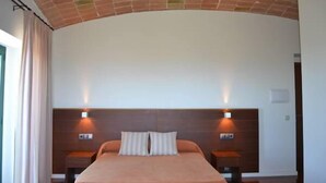 Een moderne hotelkamer met een gebogen plafond, een groot bed met twee kussens, nachtkastjes en wandlampen.