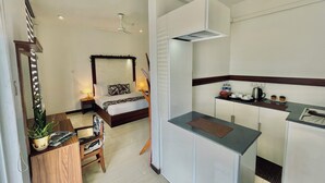 A compact hotel room with a bed, bedside table, lamp, and a small kitchenette. - 8 Plus Motels (Negombo)