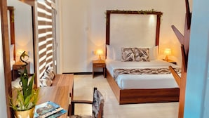 A bedroom with a bed, bedside tables, a desk, a chair, a mirror, and a potted plant. - 8 Plus Motels (Negombo)