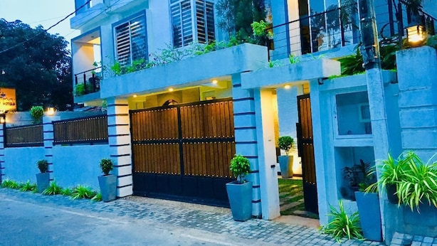 A modern two-story building with a gated entrance, potted plants, and a balcony with greenery. - 8 Plus Motels (Negombo)
