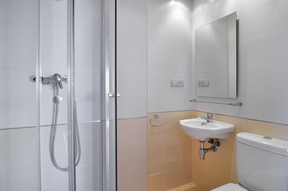A bathroom with a glass shower enclosure, a sink, and a toilet.